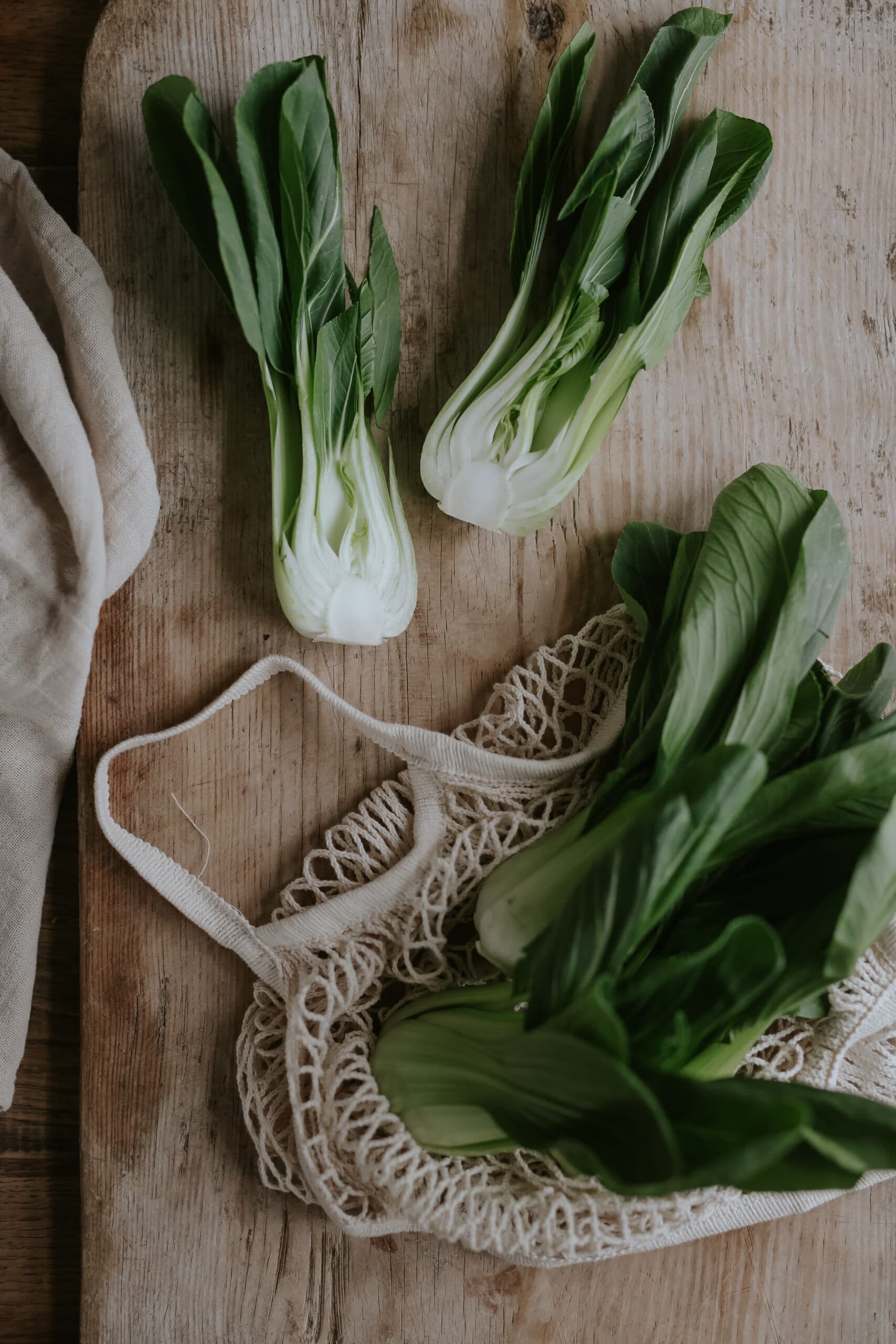 två halvor utav pak choi upplagda på brunt bord bredvid påse med fler pak choi