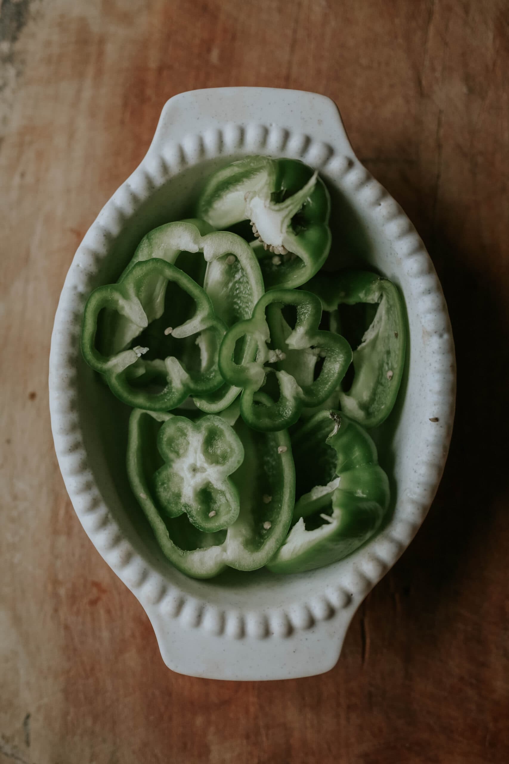 gröna paprikaskivor inuti ungsform ovanpå brunt bord